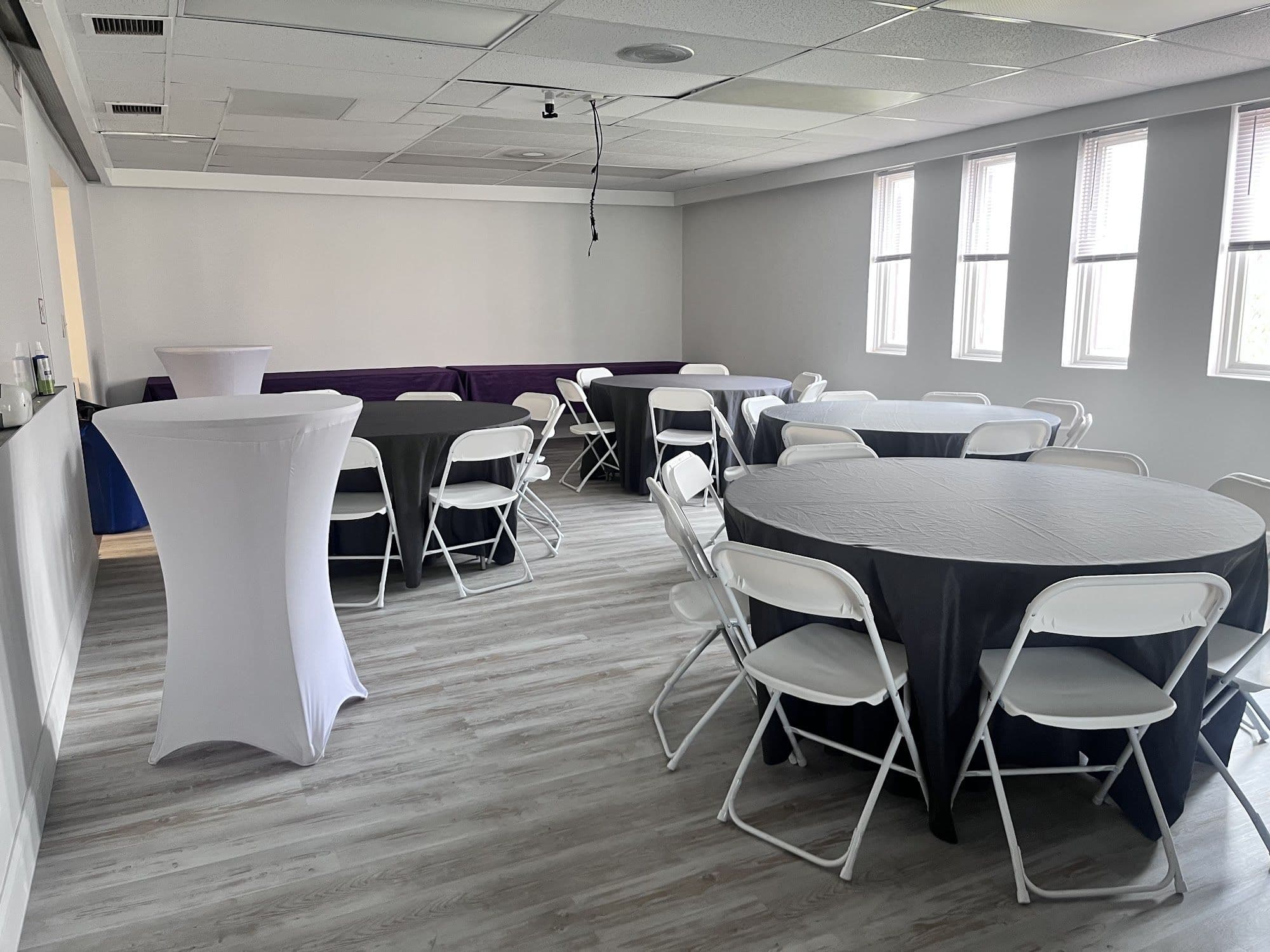 Remodeled Buffalo event space with cocktail tables, black linens and round table seating