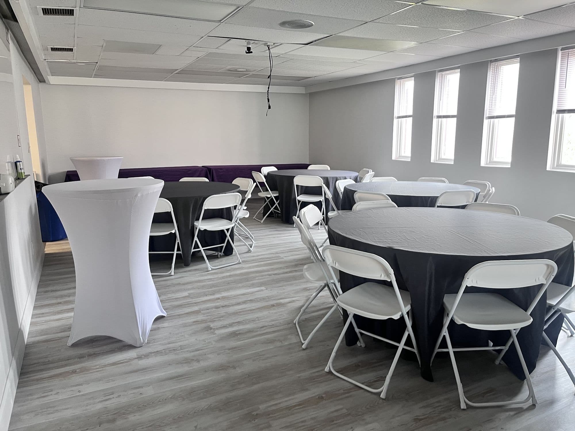 Event room layout with cocktail tables and round table seating near the windows
