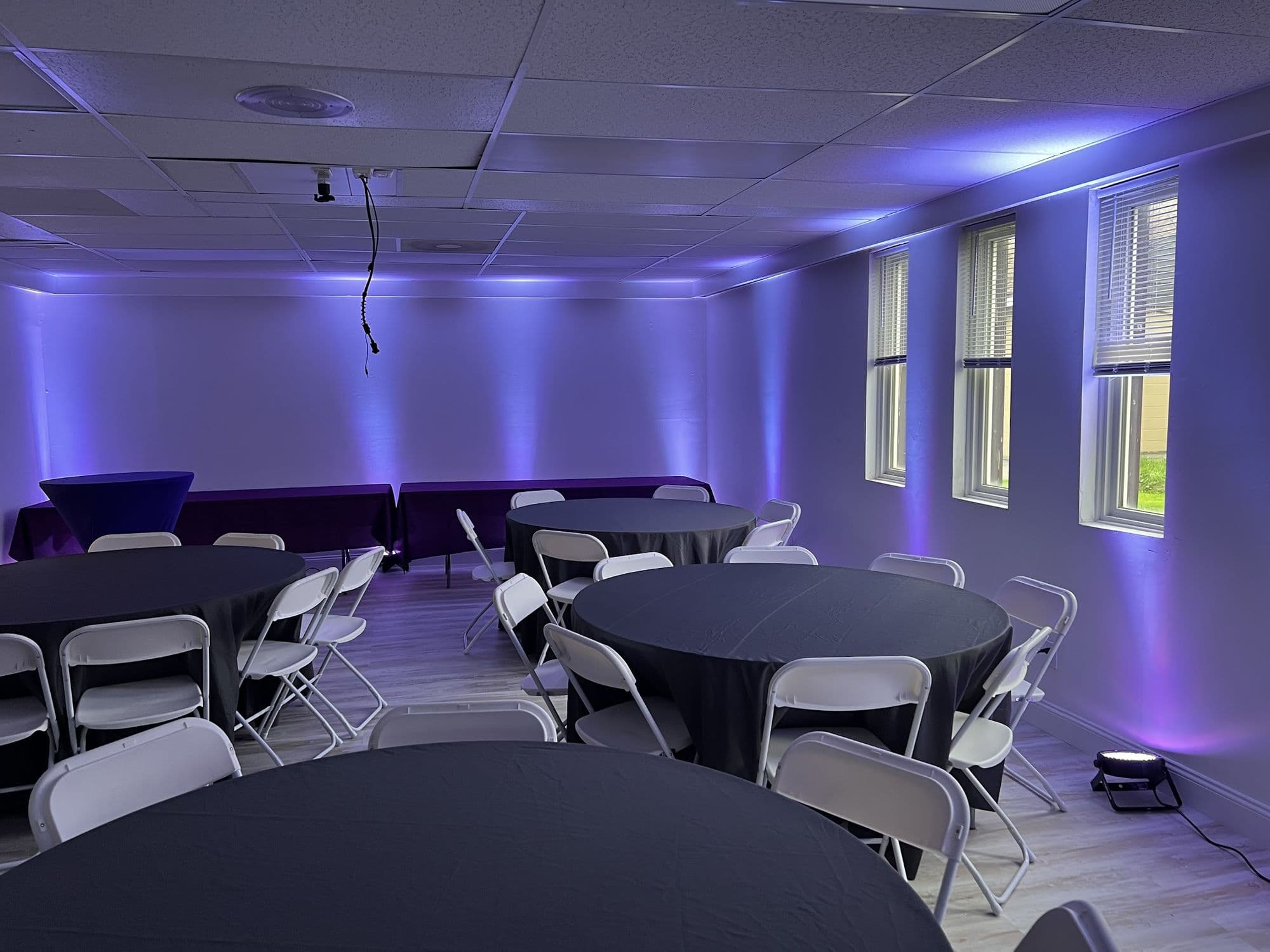 Event room in Cheektowaga with purple uplighting and round tables set for a party
