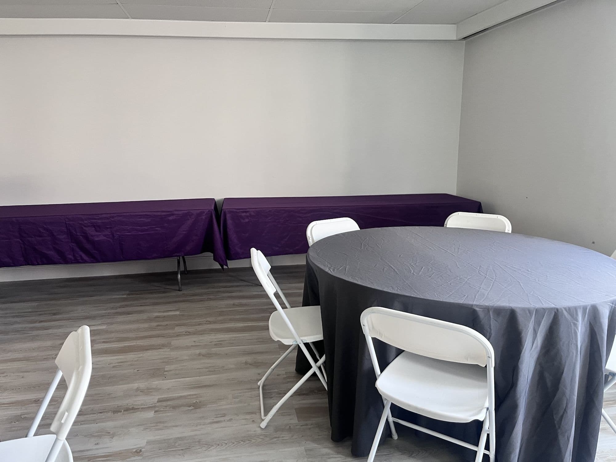 Round table with a black linen and white folding chairs in the Buffalo event room